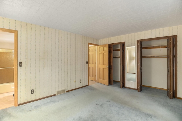 unfurnished bedroom with two closets and light colored carpet