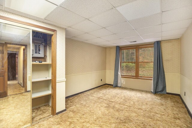 carpeted empty room with a drop ceiling