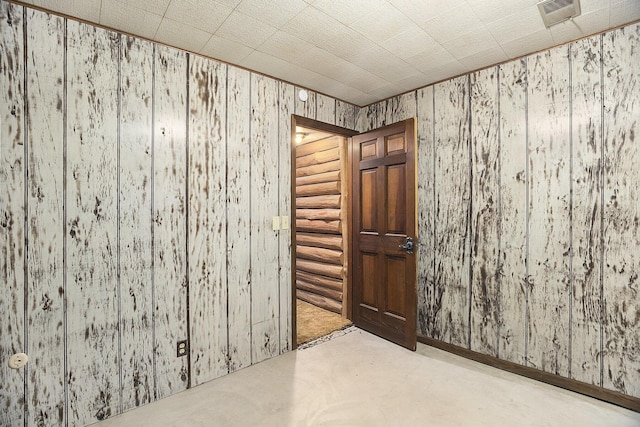 unfurnished room featuring wooden walls