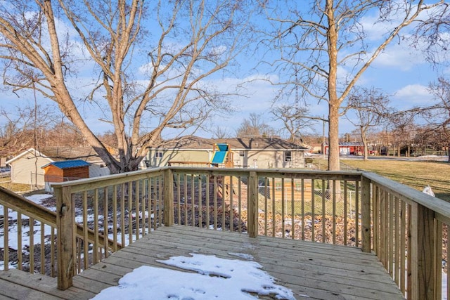 snow covered deck featuring a playground and a storage unit