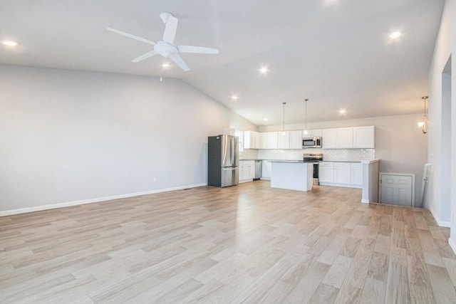 interior space with hanging light fixtures, stainless steel appliances, light hardwood / wood-style floors, white cabinets, and a kitchen island