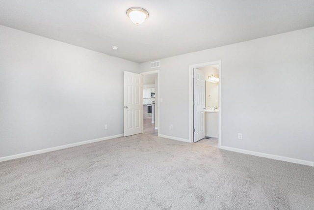 unfurnished bedroom featuring connected bathroom and light colored carpet