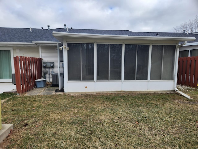 rear view of property with a lawn and a sunroom