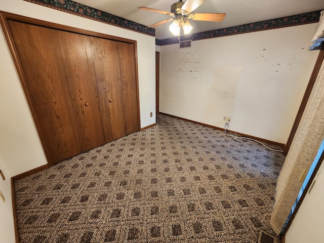 unfurnished bedroom with dark carpet, a closet, and ceiling fan