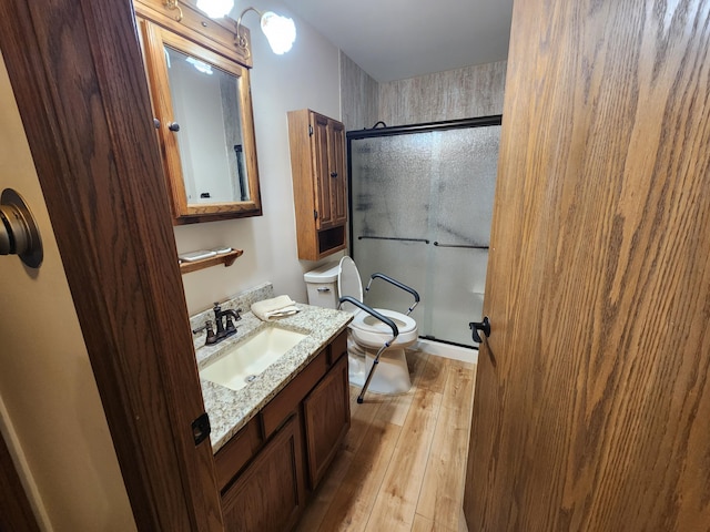 bathroom with wood-type flooring, vanity, toilet, and walk in shower