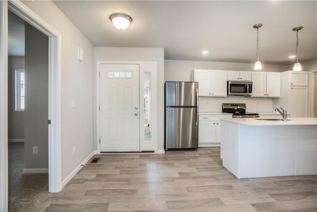 kitchen with white cabinets, appliances with stainless steel finishes, hanging light fixtures, and sink