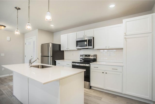 kitchen featuring white cabinets, an island with sink, hanging light fixtures, and appliances with stainless steel finishes