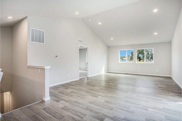 unfurnished living room with high vaulted ceiling and light wood-type flooring