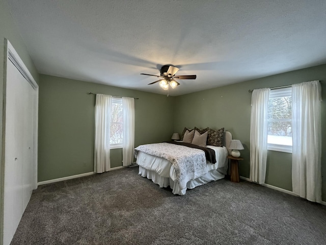 carpeted bedroom with multiple windows, a textured ceiling, ceiling fan, and a closet