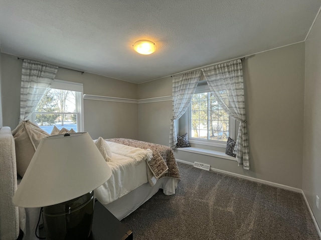 bedroom featuring a textured ceiling and dark colored carpet