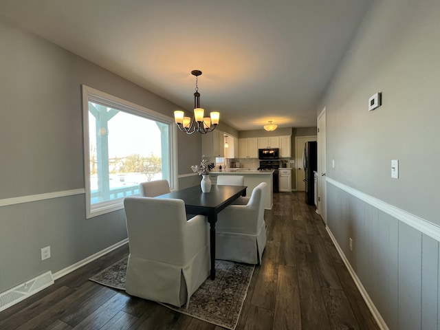 dining space with dark hardwood / wood-style floors and a chandelier