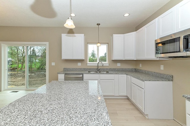 kitchen featuring appliances with stainless steel finishes, decorative light fixtures, sink, white cabinets, and a healthy amount of sunlight