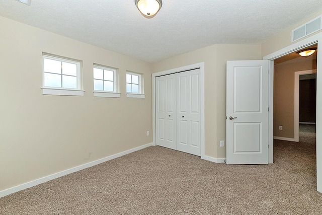 unfurnished bedroom with light colored carpet, a textured ceiling, and a closet