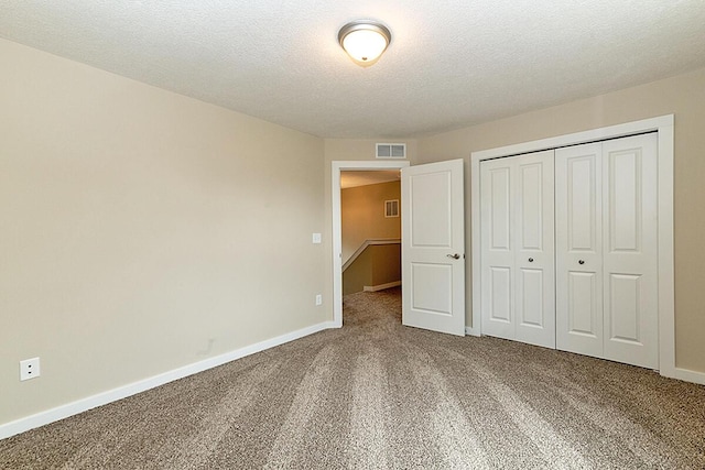 unfurnished bedroom with carpet floors, a textured ceiling, and a closet