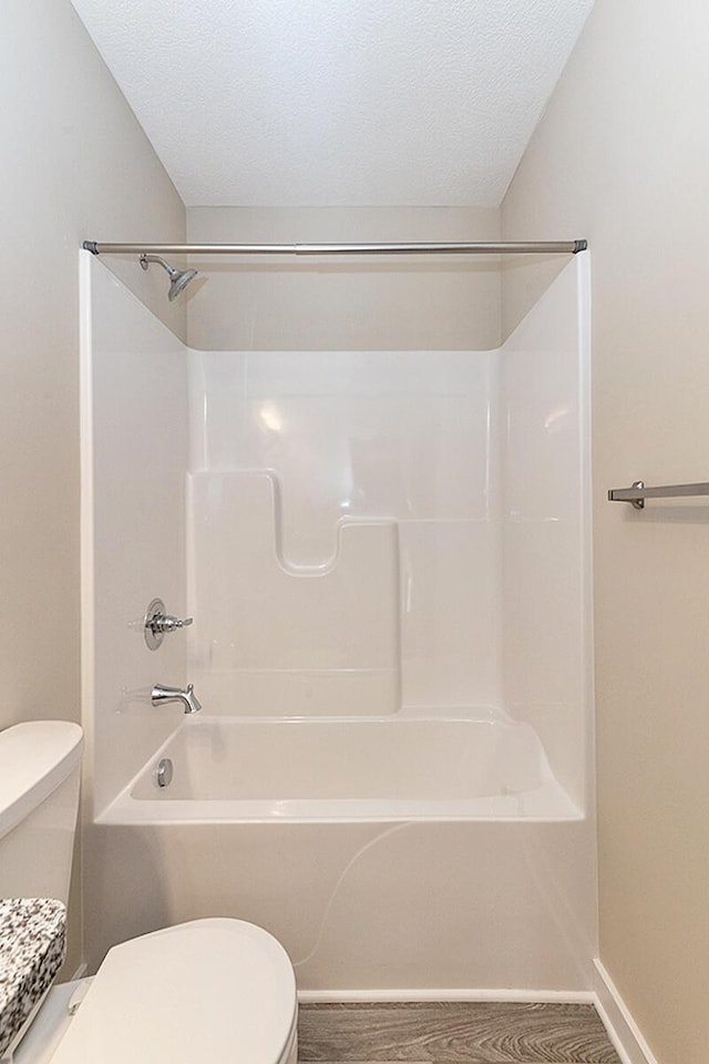 bathroom featuring shower / bath combination, hardwood / wood-style flooring, a textured ceiling, and toilet