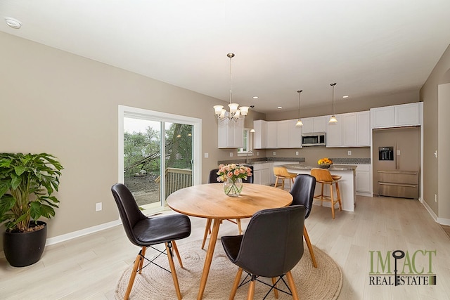 dining room featuring an inviting chandelier, sink, and light hardwood / wood-style flooring