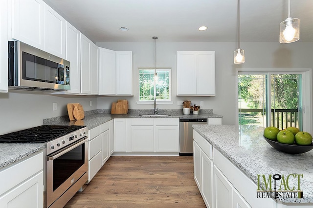 kitchen featuring sink, white cabinets, hanging light fixtures, light stone counters, and stainless steel appliances