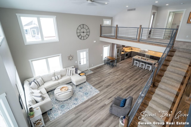 living room with hardwood / wood-style floors, ceiling fan, and a high ceiling