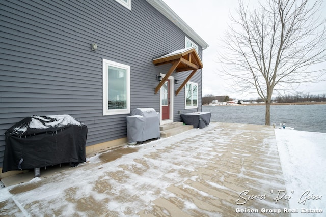 snow covered deck with area for grilling and a water view