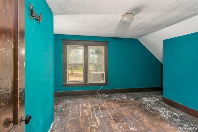 additional living space featuring dark hardwood / wood-style flooring, cooling unit, and lofted ceiling