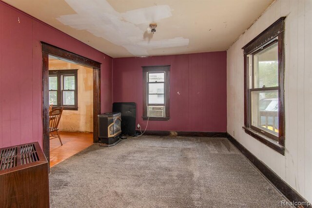 unfurnished room with carpet flooring and a wood stove