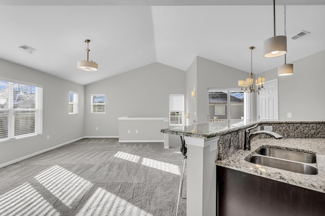 kitchen with light stone countertops, sink, an inviting chandelier, light colored carpet, and decorative light fixtures