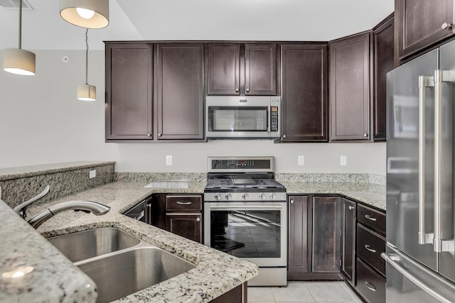 kitchen featuring dark brown cabinetry, sink, stainless steel appliances, light stone counters, and decorative light fixtures