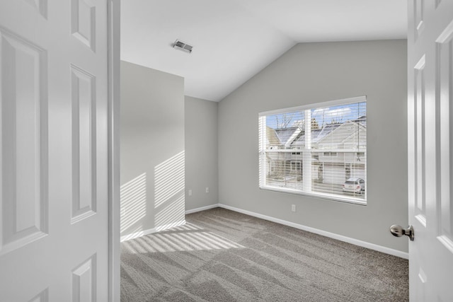 spare room featuring carpet and lofted ceiling