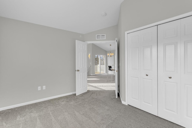 unfurnished bedroom featuring carpet floors, an inviting chandelier, a closet, and lofted ceiling