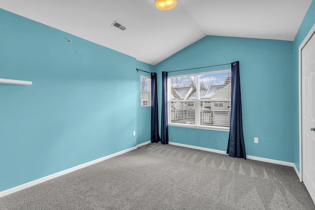 carpeted spare room with vaulted ceiling