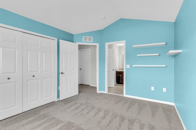 unfurnished bedroom with light carpet, a closet, and vaulted ceiling