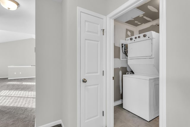 laundry area featuring light tile patterned floors and stacked washer and clothes dryer