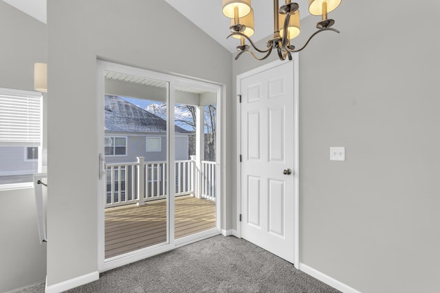 entryway with carpet floors, a chandelier, and vaulted ceiling