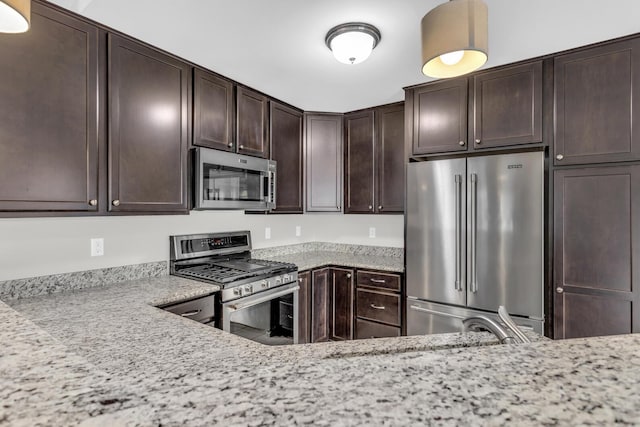 kitchen featuring dark brown cabinets, light stone countertops, and appliances with stainless steel finishes