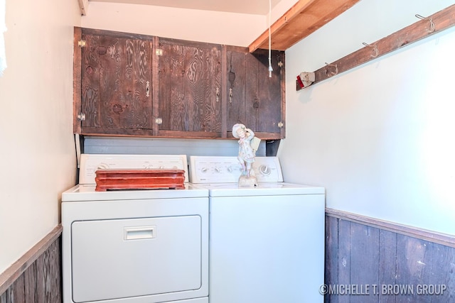 laundry room featuring cabinets, washing machine and dryer, and wooden walls