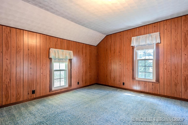 spare room featuring plenty of natural light, carpet flooring, and vaulted ceiling