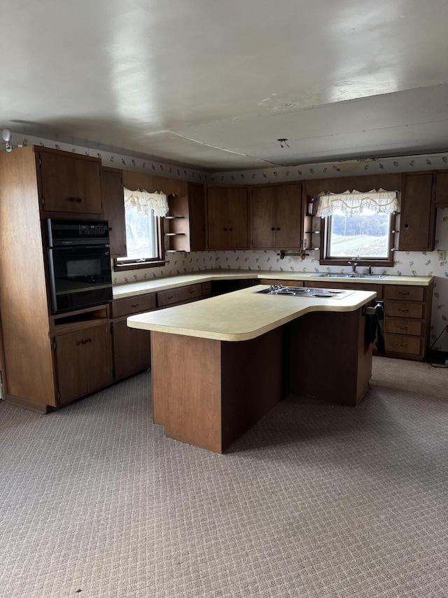 kitchen featuring light carpet, gas cooktop, black oven, and a kitchen island