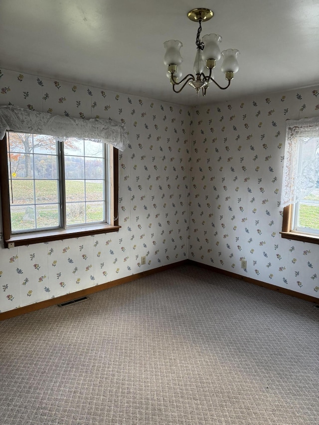 carpeted spare room with an inviting chandelier