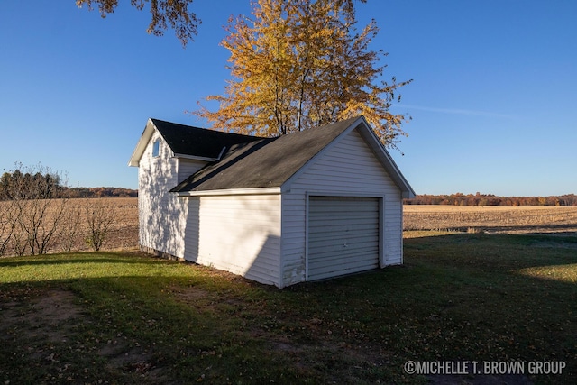 garage featuring a rural view and a yard