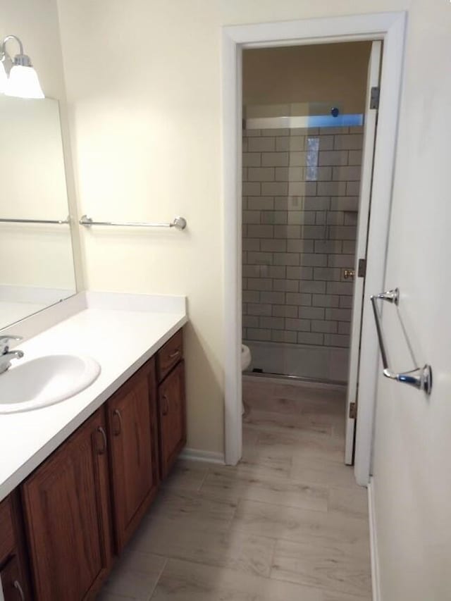 bathroom with a tile shower, vanity, and toilet