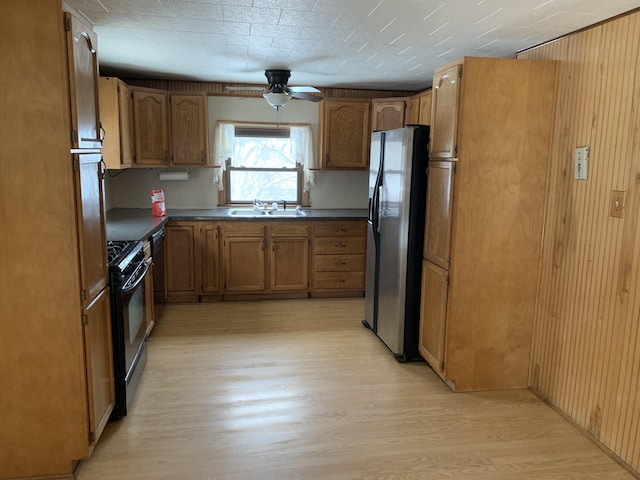 kitchen featuring black gas range, sink, stainless steel refrigerator with ice dispenser, ceiling fan, and light hardwood / wood-style floors