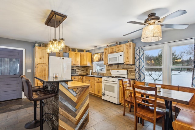 kitchen featuring ceiling fan, sink, hanging light fixtures, white appliances, and decorative backsplash