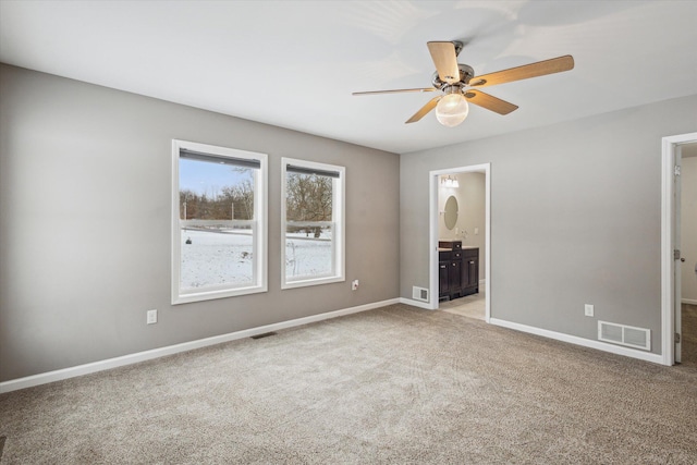 unfurnished bedroom with ceiling fan, light colored carpet, and ensuite bath