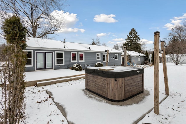 snow covered back of property featuring a hot tub