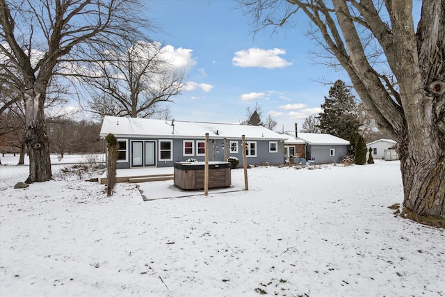 snow covered back of property featuring a hot tub and a deck