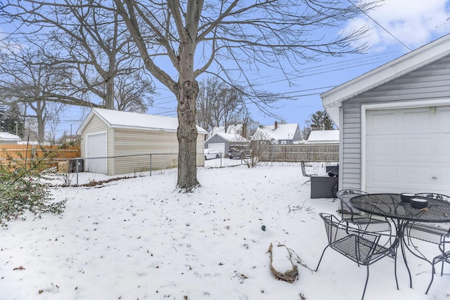 yard layered in snow with a garage and an outdoor structure