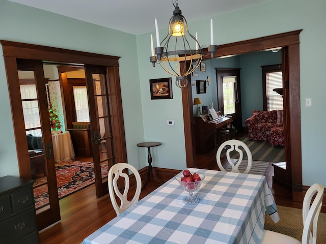 dining space featuring dark hardwood / wood-style flooring, french doors, and an inviting chandelier