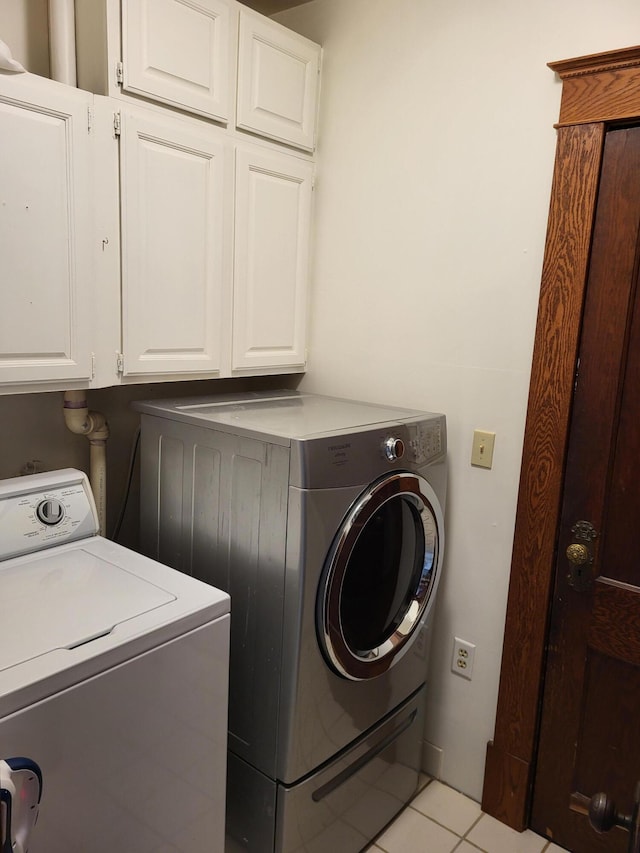 laundry area with washer and clothes dryer, cabinets, and light tile patterned floors