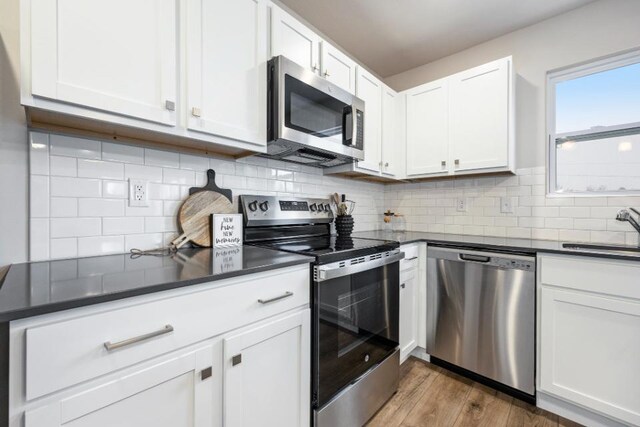 kitchen with white cabinetry, appliances with stainless steel finishes, sink, and light hardwood / wood-style flooring