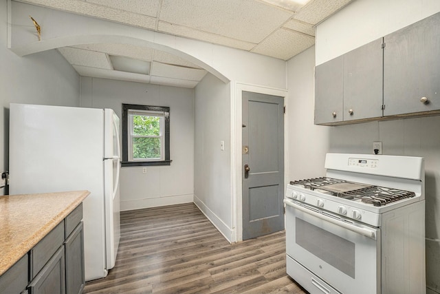 kitchen featuring a drop ceiling, hardwood / wood-style floors, white appliances, and gray cabinetry